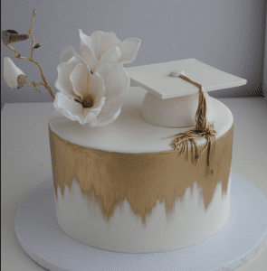 A cake with a flower and a cap on top of it.