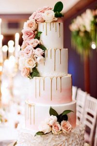 A tall white cake with pink flowers on top