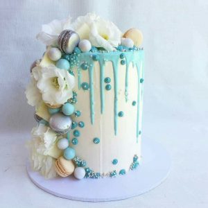 A cake with white and blue frosting on top of a table.