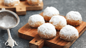 A wooden board with powdered donuts on it.