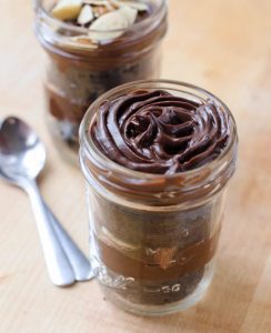 A jar of chocolate pudding with spoon on the side.