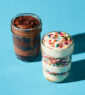 Two jars of different flavors of ice cream on a blue surface.