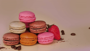 A stack of different colored macaroons next to a strawberry.