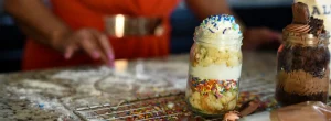 A jar of cake with sprinkles on top.