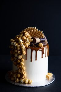 A white cake with caramel and chocolate on top.