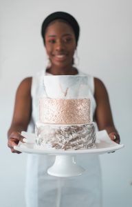 A woman holding a cake on top of a white plate.