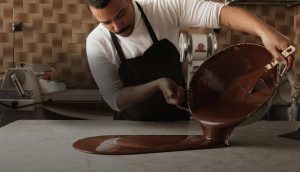 A man in an apron is making chocolate.